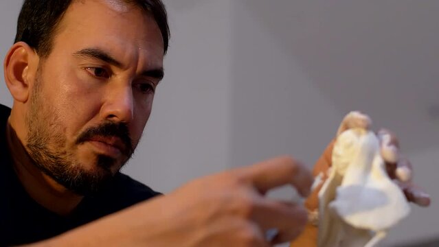 Experience the finesse of a Latino sculptor refining the figure's hair with a knife. Delve into the artistic mastery and cultural influence shaping this captivating sculpting technique. 