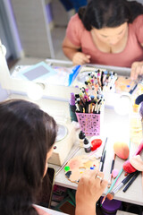 Latina woman is choosing the color of the foundation she will apply, with the focus on the brushes and other tools that are necessary for the makeup process