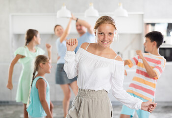 Happy teenage girl dancing together with her sisters, brothers and parents in the living room