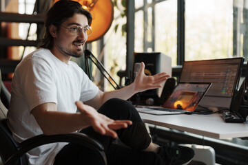 Fototapeta na wymiar Music producer in the studio, explaining a concept with hands gesturing, amidst professional recording equipment