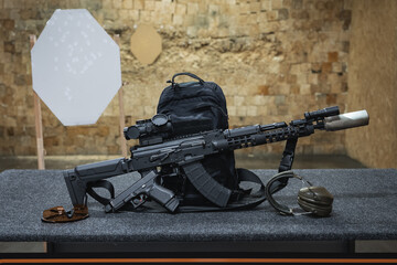 Tactical shooting and firearms in a shooting range, AKM rifle with optical sight and 9mm pistol.