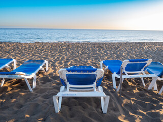 Seaside Relaxation with Blue Lounge Chairs during Sunset in Spain