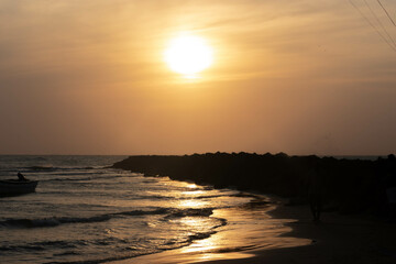 people in silhouette on the beach next to the sea with sunset. Cartagena Colombia.