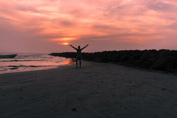 people in silhouette on the beach next to the sea with sunset. Cartagena Colombia.