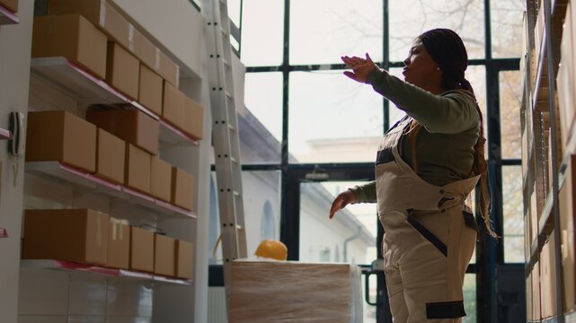 Manager in warehouse using AR holographic technology to visualize how to best stash parcels on shelves to make room for more. Supervisor in distribution center uses augmented reality