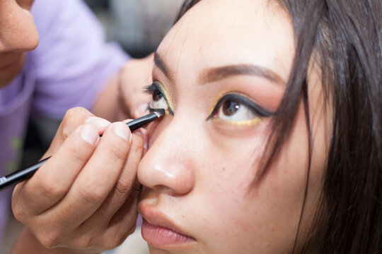 Photo of young girl being made up, painted eyes. Concept of people and beauty.