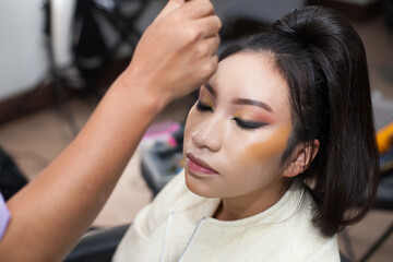 Fototapeta premium Photo of a woman being made up with a brush in a spa or beauty salon. Concept of women, beauty and self love.
