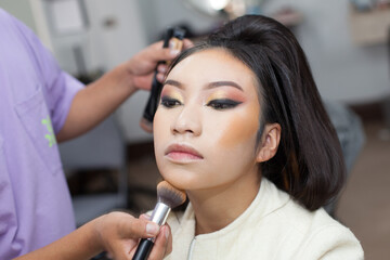 Photo of a woman being made up with a brush in a spa or beauty salon. Concept of women, beauty and...