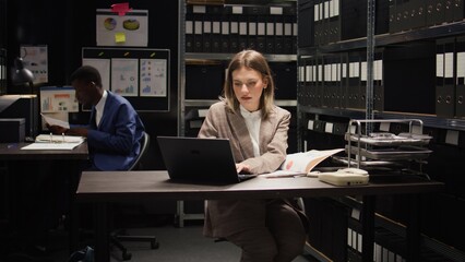 In office, detective inspector and male police officer conduct an investigation, expertly analyzing...
