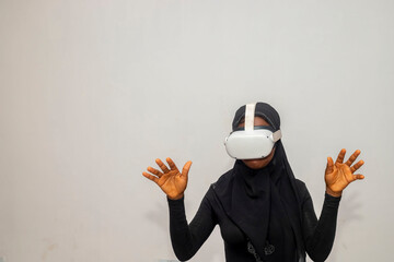 Excited young African muslim lady on hijab using VR glasses, touching something invisible at copy...