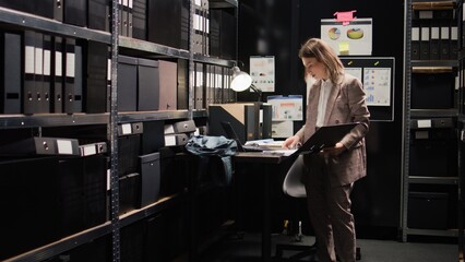 Caucasian policewoman conducts investigative legal work with confidential papers, working on a...