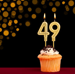 Birthday candle with cupcake - Number 49 on black background with out of focus lights