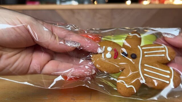 gingerbread man Gift for Christmas delicious cookies take out from packaging dance beautiful toy delicacy female hands with shiny Christmas manicure Present yami. symbol of winter New Year