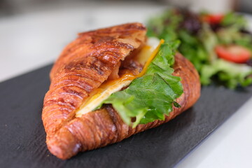 4K Breakfast Scene. A woman is eating a croissant with bacon and scrambled eggs at breakfast.