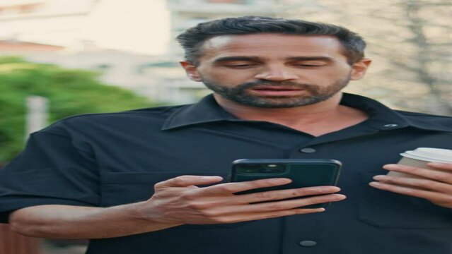 Relaxed man talking phone video call walking park with coffee vertical closeup