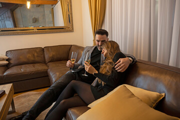 Happy, romantic, smiling couple drinking champagne , sitting on the sofa