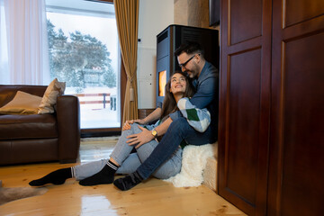 Romantic couple enjoying together in mountain house by the fire on a cold winter day