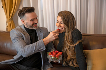Naklejka premium Handsome man feeding his girlfriend with strawberry
