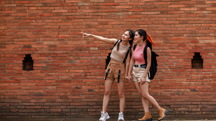 two asian tourist girl standing posing and pointing hand at the tha phae gate, chiang mai thailand,