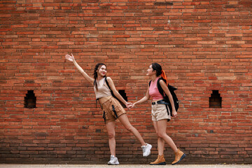 two asian tourist girl standing posing and pointing hand at the tha phae gate, chiang mai thailand,