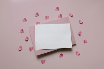Top view photo. Valentines day, baby shower decoration. Blank greeting card, invitation mockup, envelope. Pink cut out folded paper hearts confetti isolated on pastel background. Flat lay, copy space