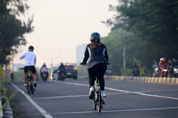 rear view of man cycling in the morning with morning sunlight. cycling to maintain fitness and a healthy lifestyle.