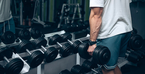 Young man exercising with dumbbells in the gym with dumbbells
