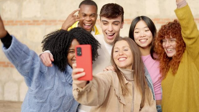 Multi-ethnic young friends celebrating while taking a selfie outdoors