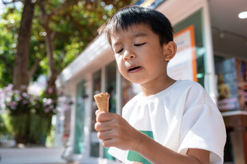 Asian boy kid hold scoops of strawberry and vanilla ice cream in waffles cone