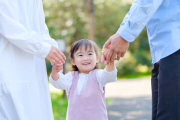 Fototapeta premium 家族で手を繋いで歩く女の子