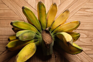 Pisang Kepok Kuning (musa acuminata) or yellow local banana on the wooden table. bananas can be made into delicious and nutritious food preparations. Indonesian fruit. 