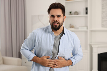 Young man suffering from stomach pain indoors