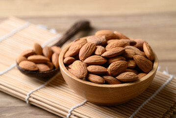 Raw almond in bowl with spoon on wooden background