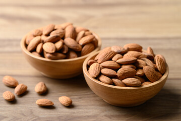 Raw almond in bowl on wooden background