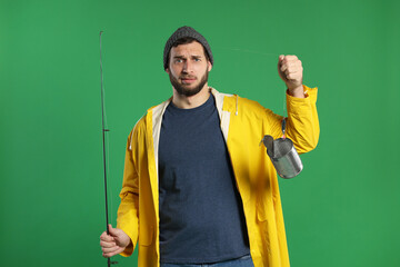 Confused fisherman with fishing rod and tin can on green background