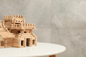 Wooden castle on white table, space for text. Children's toy