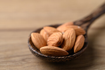 Raw almond in spoon on wooden background, Close up