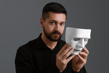 Multiple personality concept. Man with mask on grey background