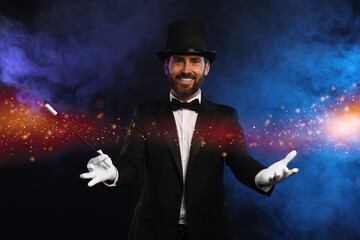 Smiling magician with wand showing trick on dark background