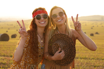Beautiful happy hippie women showing peace signs in field