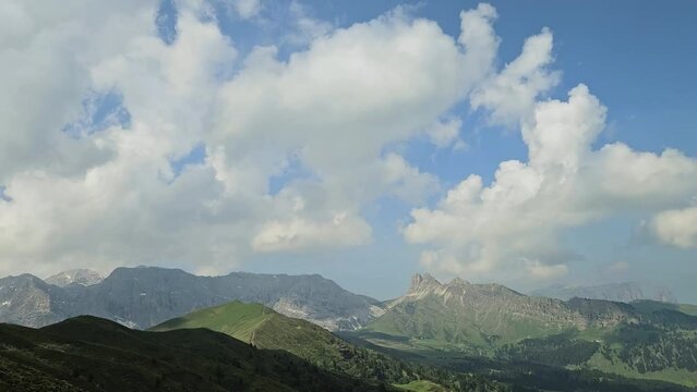Time lapse of white clouds passing by in Italian Dolomites, casting shadows on the hills below. Scenic and breathtaking view.