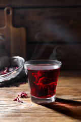 Delicious hibiscus tea in glass on wooden table. Space for text