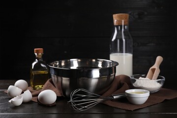 Making dough. Metal whisk and ingredients on dark wooden table