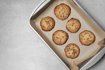 Baking pan with chocolate chip cookies on gray table, top view. Space for text
