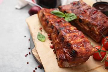 Tasty roasted pork ribs served with basil on grey table, closeup. Space for text