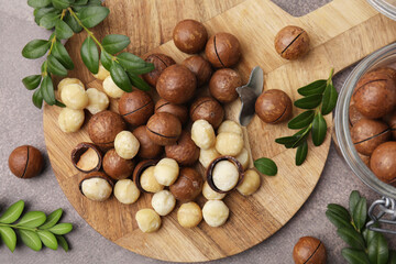 Tasty Macadamia nuts and green twigs on grey table, flat lay