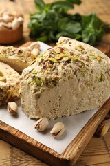 Tasty halva with pistachios and mint on table, closeup