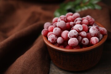 Frozen red cranberries in bowl on table, closeup