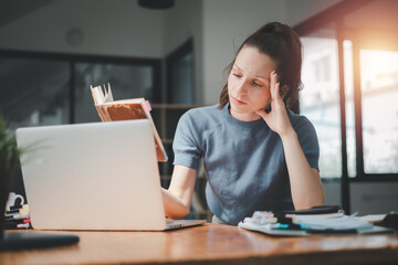 Businesswoman is serious at work causing headaches and stressed out with documents with a laptop at the office