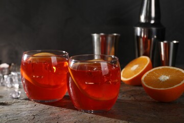 Aperol spritz cocktail, ice cubes and orange slices in glasses on grey textured table